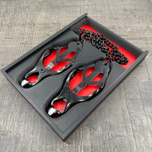 Een set zwarte tepelklemmen in een doosje