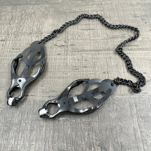 Een set zwarte clover-clamps tepelklemmen met een ketting