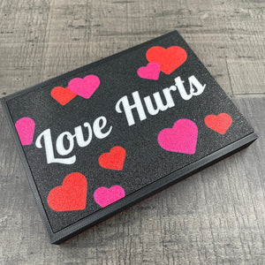 Een doosje met de tekst "Love Hurts"