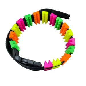 Een BDSM cilice met een zwarte band en spikes in UV-reactieve kleuren
