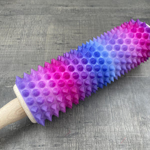 Een deegroller met spikes voor BDSM met een kleurverloop van paars, blauw en roze