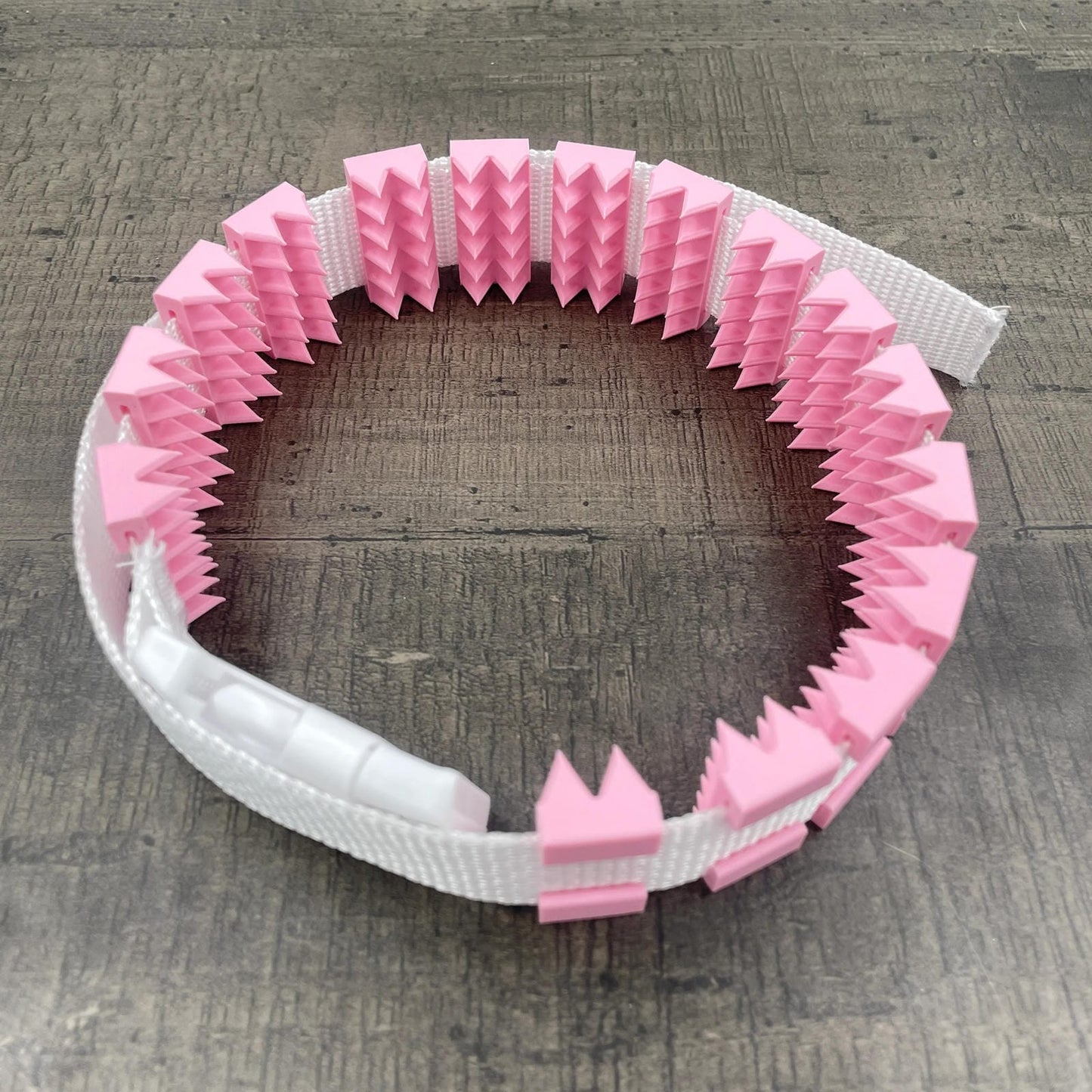 Een BDSM cilice met een witte band en roze spikes