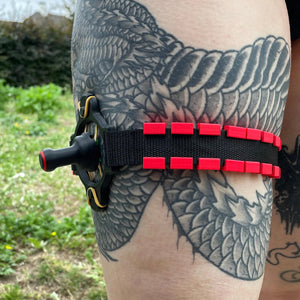 Een zwarte band met een BDSM impact speeltje met spikes om het been van een persoon