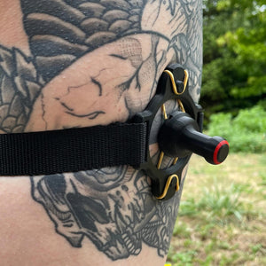 Een zwarte band met een BDSM impact speeltje met spikes om het been van een persoon