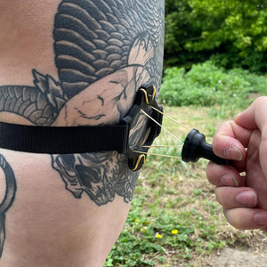 Een zwarte band met een BDSM impact speeltje met spikes om het been van een persoon