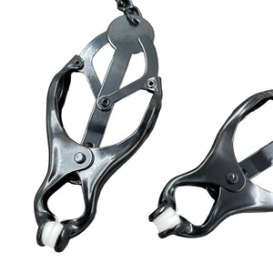 Een set zwarte clover clamps tepelklemmen, verbonden met een zwarte ketting.
