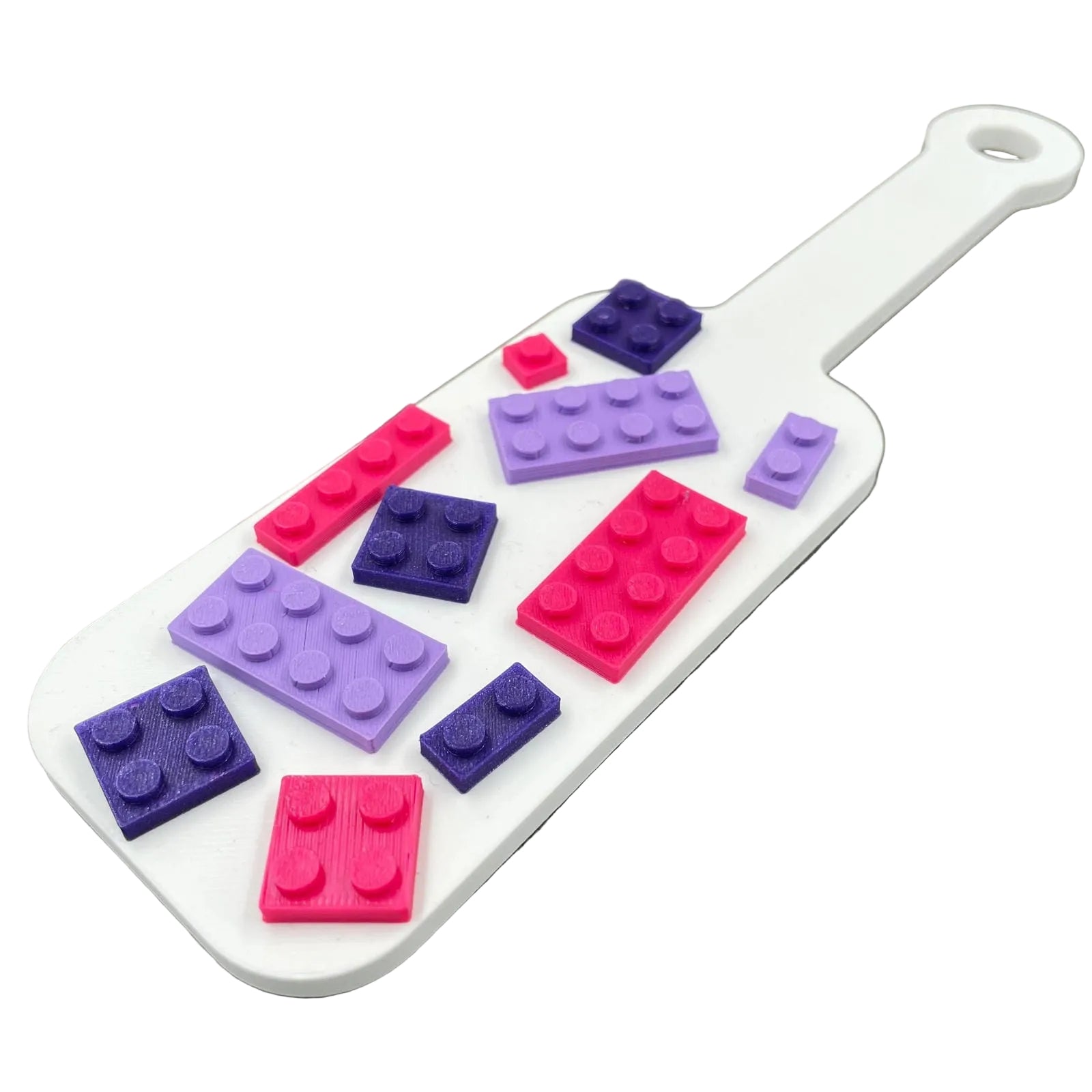 Een kleine BDSM-paddle in de kleur wit met paarse en roze bouwsteentjes