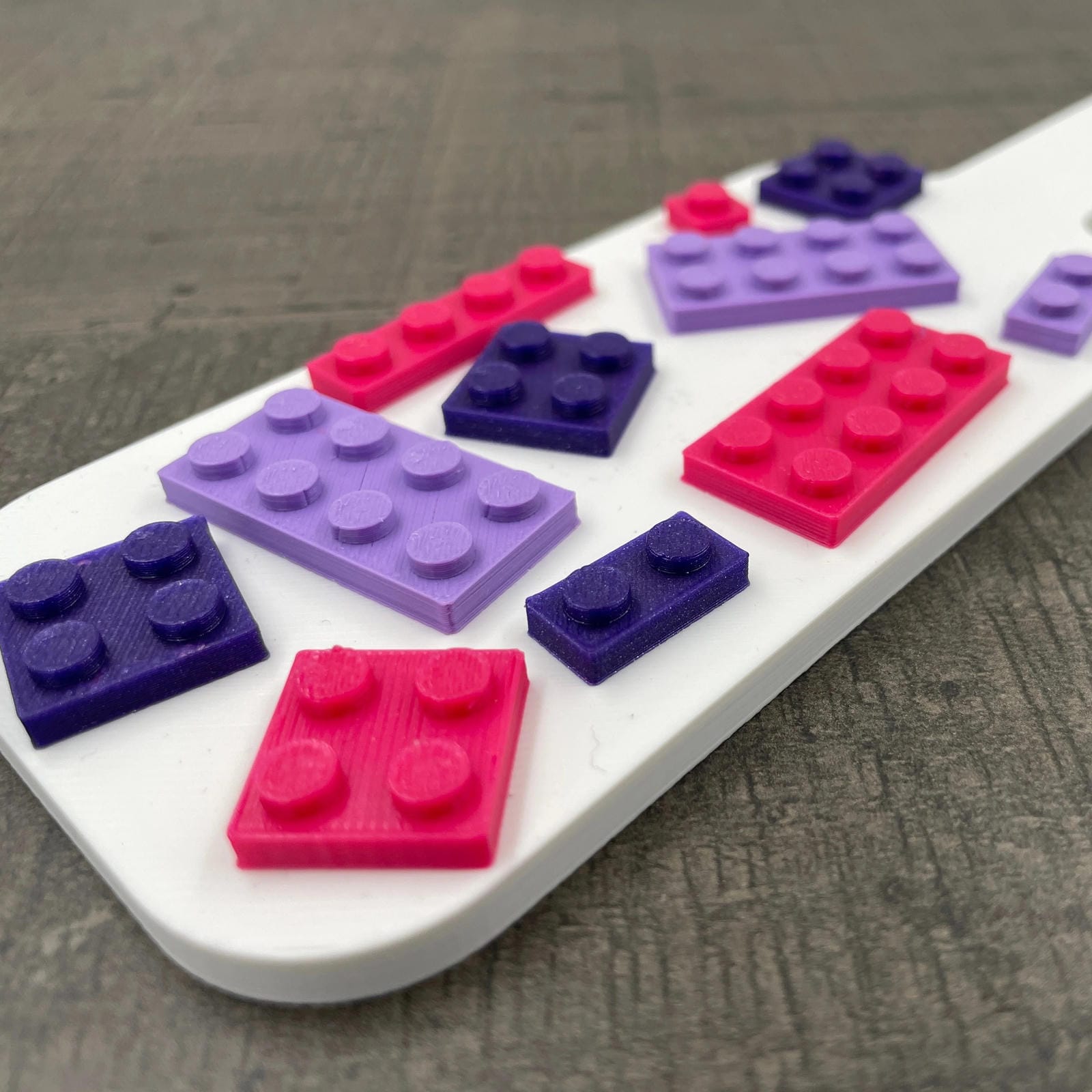 Een kleine BDSM-paddle in de kleur wit met paarse en roze bouwsteentjes