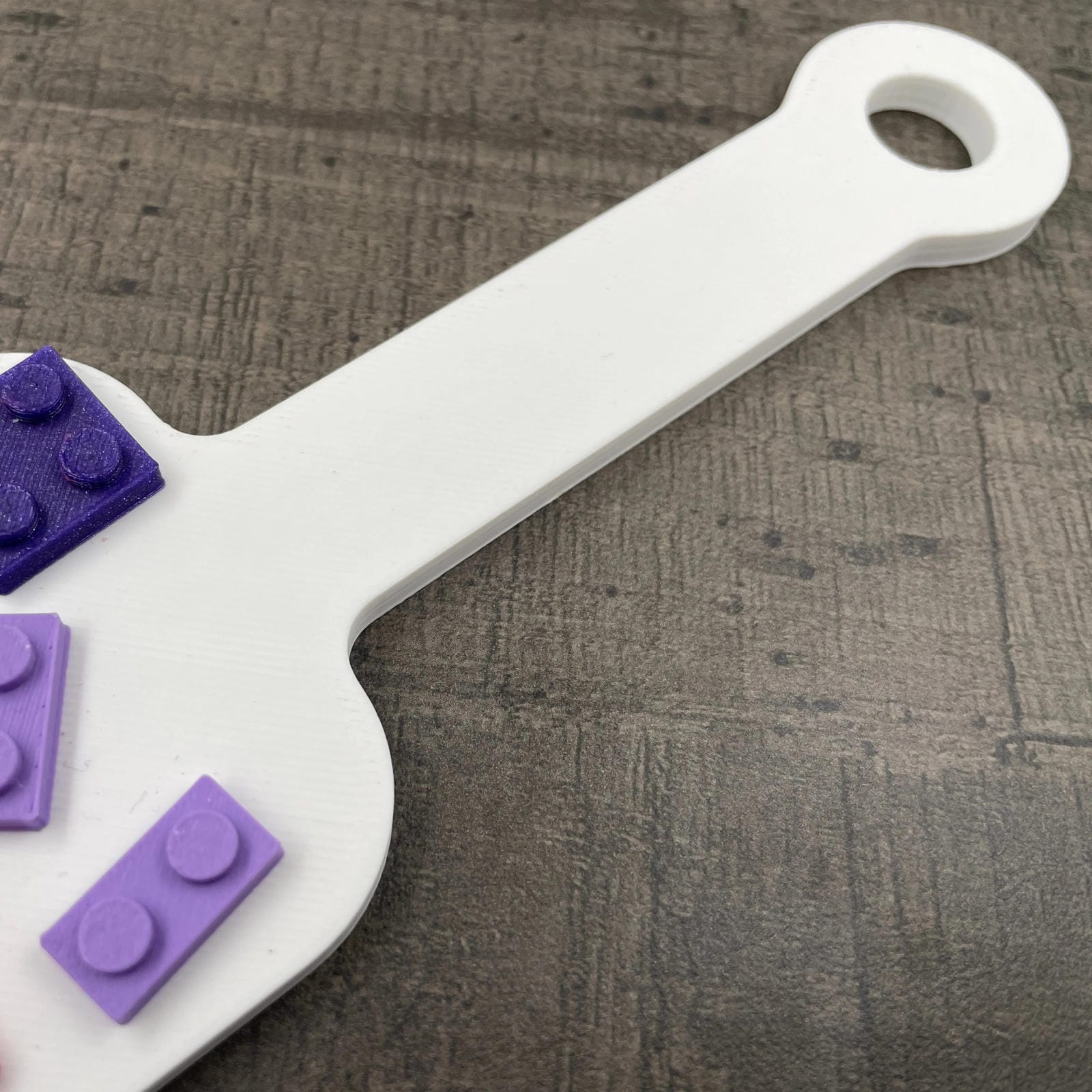 Een kleine BDSM-paddle in de kleur wit met paarse en roze bouwsteentjes