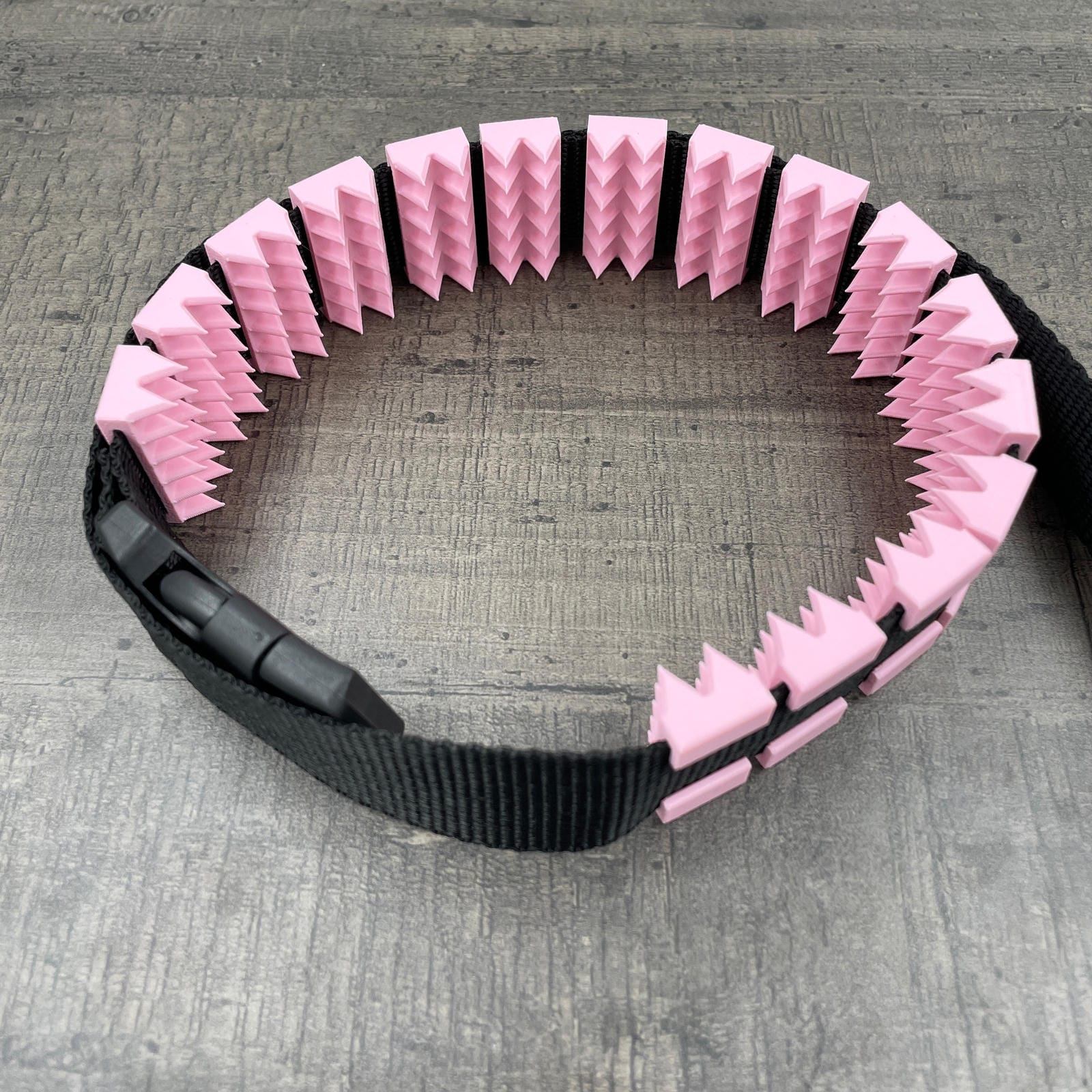 Een BDSM cilice met een zwarte band en spikes in de kleur roze