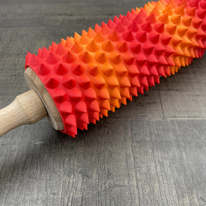 Een deegroller met spikes voor BDSM in de kleuren rood en oranje