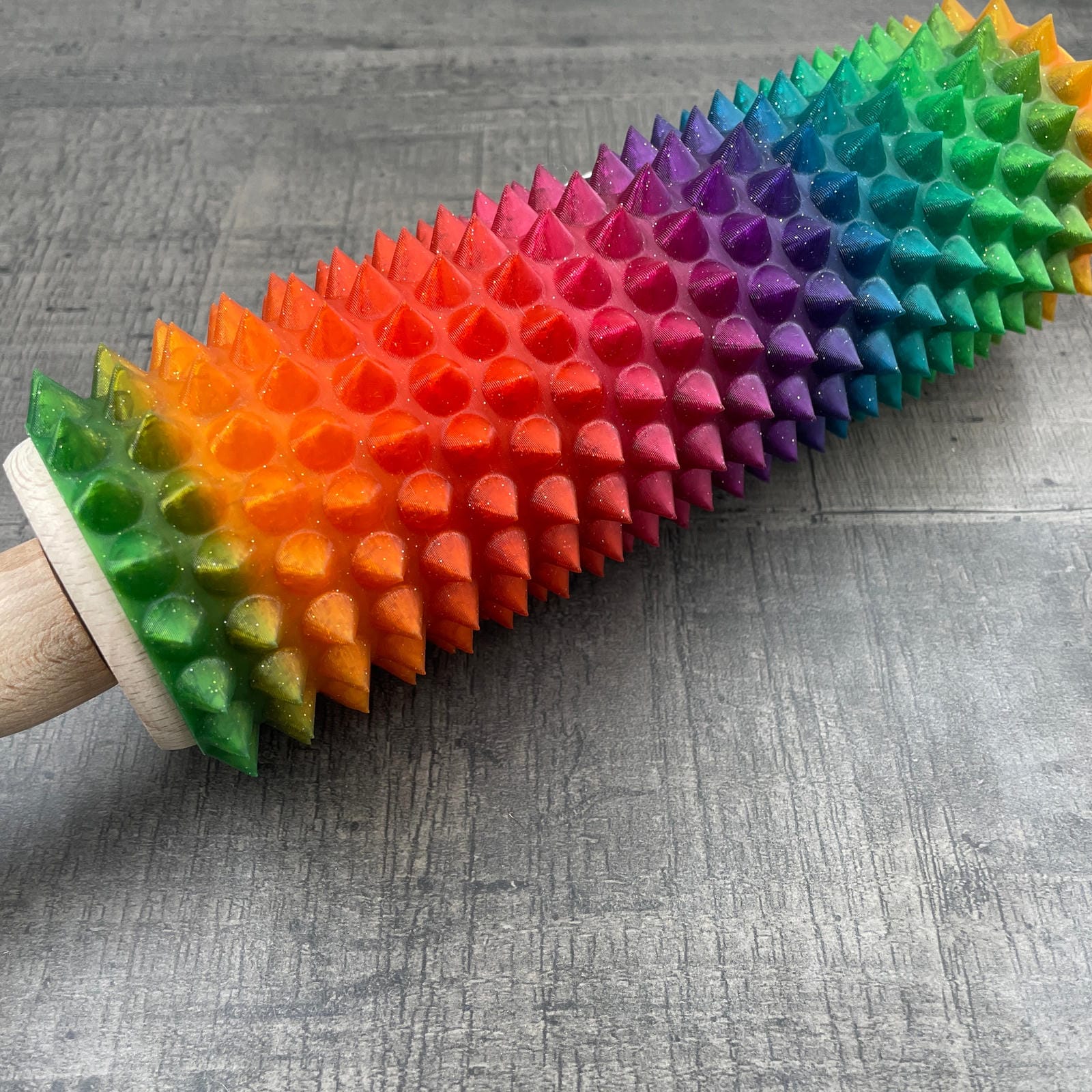 Een deegroller met spikes voor BDSM met regenboogkleuren en glitters