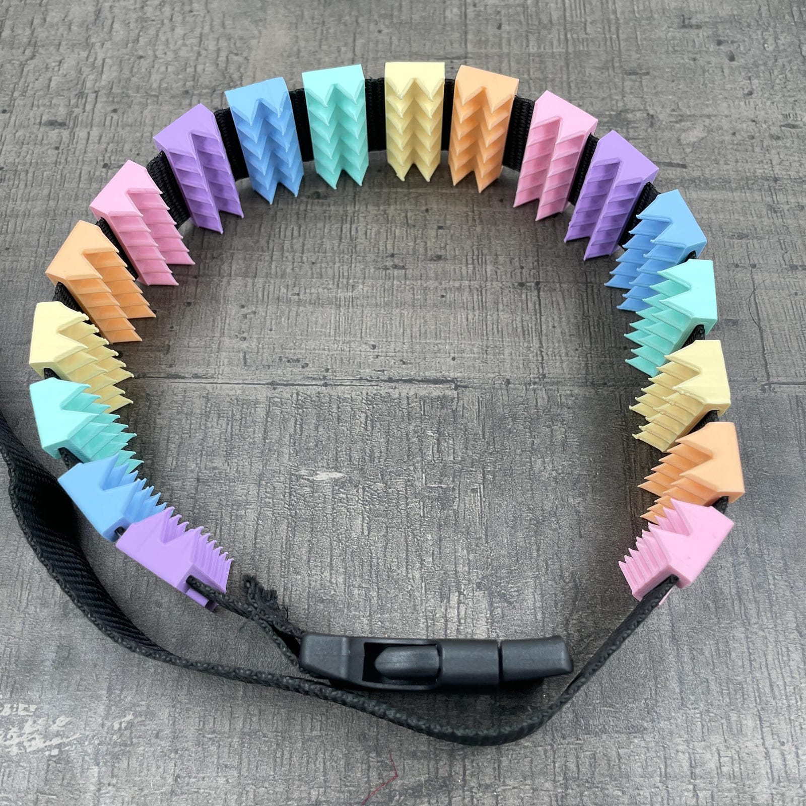 Een BDSM cilice met een zwarte band en spikes in pastelkleuren
