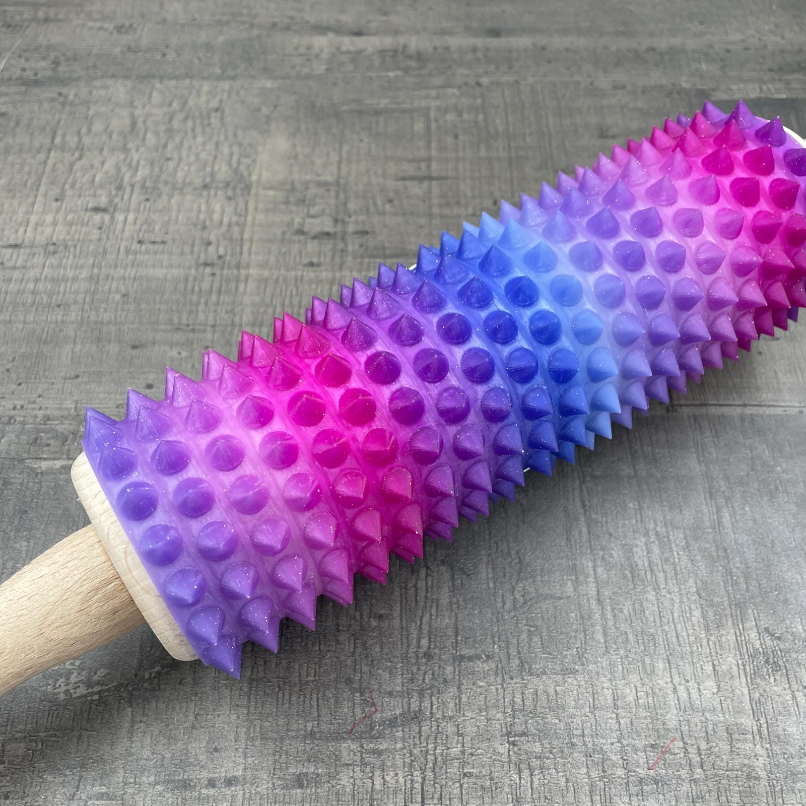 Een deegroller met spikes voor BDSM met een kleurverloop van paars, blauw en roze