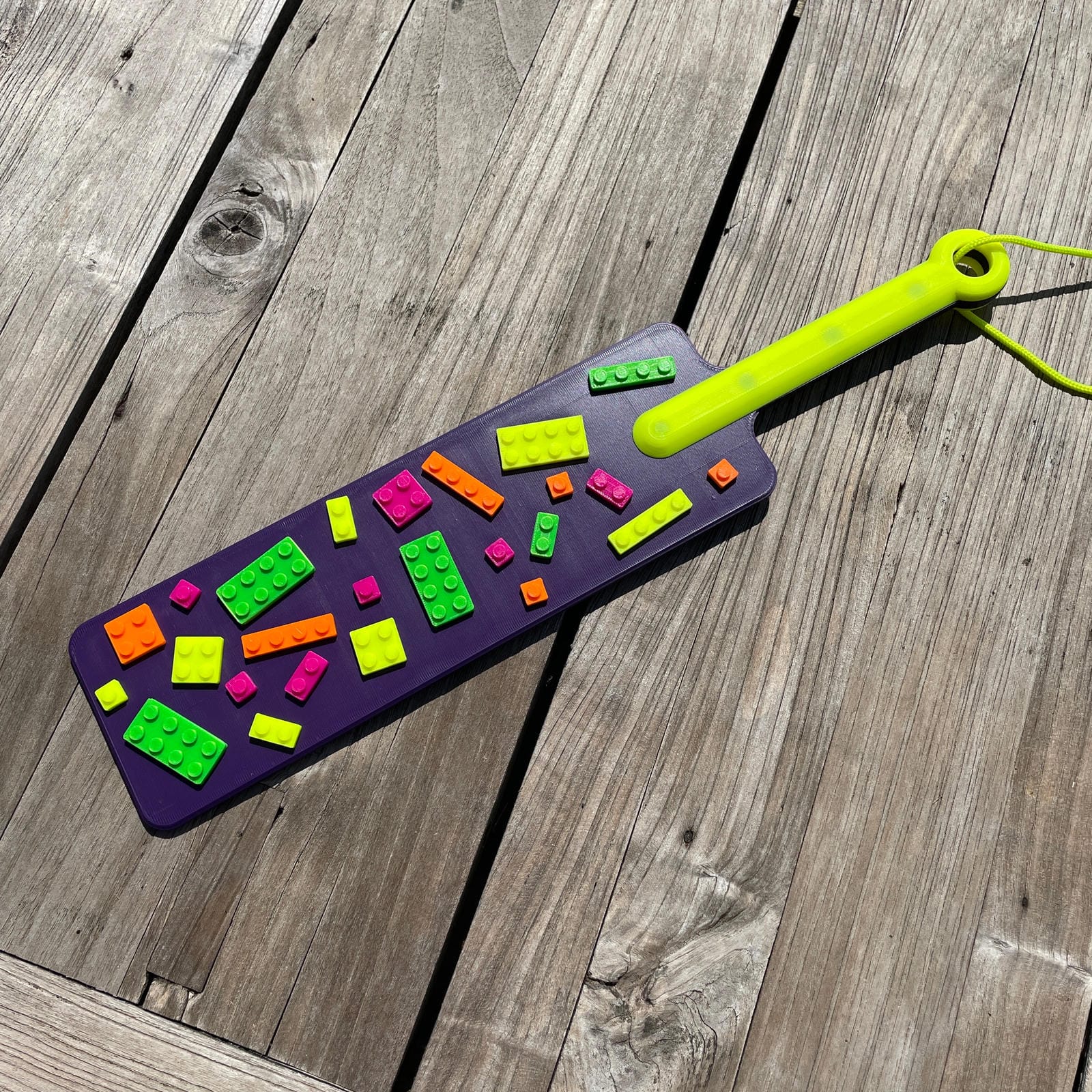 Een BDSM paddle in paars met UV-reactieve bouwsteentjes