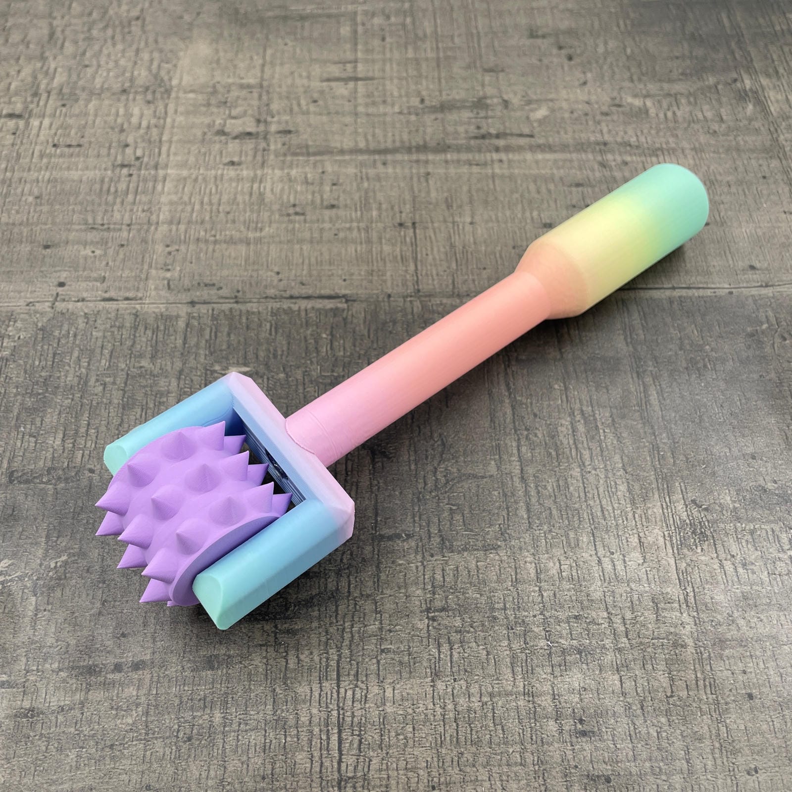 Een BDSM pinwheel met een pastel-kleurig regenboog handvat en een lila wieltje